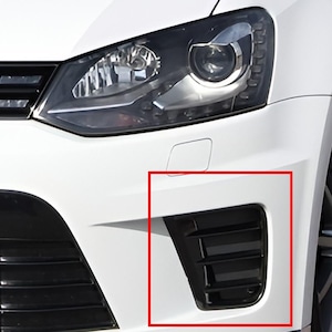 May include: Close-up of a white car's front bumper with a black air vent. The vent has horizontal slats and is located below the headlight. The car's headlight is visible.