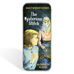 May include: A rectangular tin featuring the cover art of "The Mysterious Stitch" by Carolyn Keene. The cover art depicts a young woman looking at a woman in a headscarf. The tin is dark green with gold lettering.