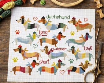 May include: A cross-stitch pattern on white fabric featuring twelve dachshund dogs in various colors, with the text "dachshund long wiener short love" in red and green. The design includes small red hearts and paw prints, surrounded by embroidery supplies.