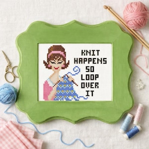 May include: A cross-stitch embroidery in a light green scalloped frame featuring a cartoon figure knitting with blue yarn. The text reads: KNIT HAPPENS SO LOOP OVER IT. The design includes a pink headband, a blue patterned sweater, and brown hair.