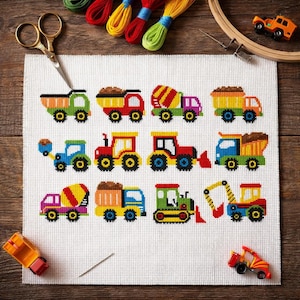 May include: A white Aida fabric square featuring a cross-stitch pattern of twelve colourful construction vehicles, including dump trucks, cement mixers, and excavators, arranged in three rows, accompanied by gold scissors and embroidery floss.