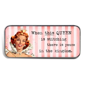 May include: A pink and white striped background with a vintage illustration of a woman wearing a crown and a cape. The text reads "When this QUEEN is stitching there is peace in the kingdom."