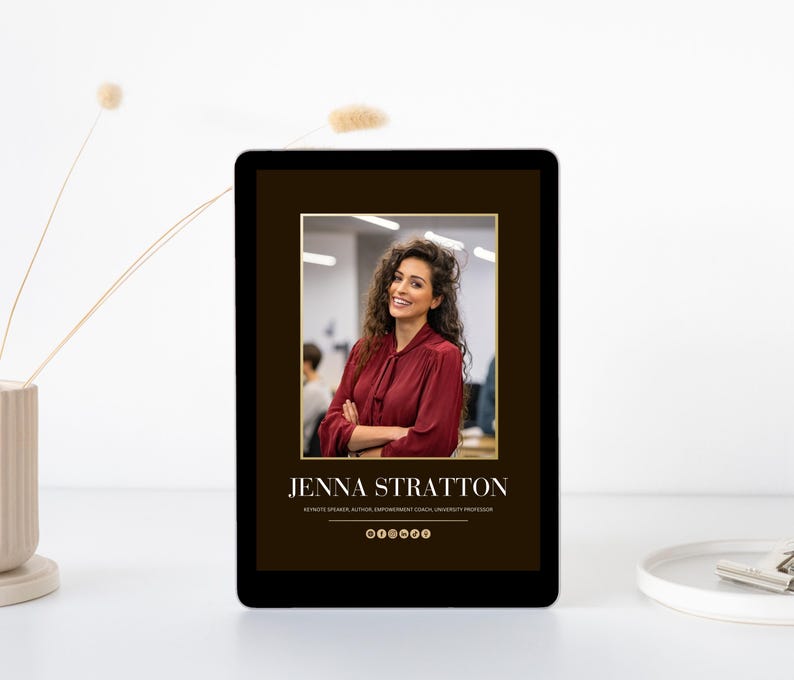 May include: A digital tablet displays a portrait of a woman with curly hair wearing a burgundy blouse. The text "JENNA STRATTON" is below the image, along with her credentials. The tablet is on a white surface with a vase and decorative sprigs.