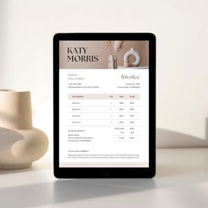 May include: A digital tablet displays an invoice template with the name "KATY MORRIS" at the top. The invoice includes sections for services, quantities, and totals. A beige ceramic vase is on the left.