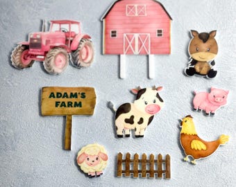 May include: A set of farm-themed cake toppers, including a red tractor, a pink barn, a brown horse, a black and white cow, a pink pig, a yellow chicken, a white sheep, a brown fence, and a wooden sign that says "Adam's Farm".