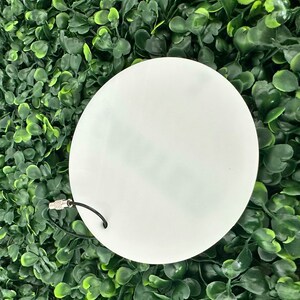 Pu&ograve; includere: Un ornamento bianco rotondo vuoto per sublimazione con una corda nera attaccata a un anello di metallo argentato.