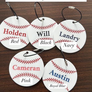 Pu&ograve; includere: Cinque ornamenti bianchi a tema baseball con cuciture rosse e ganci in corda nera. Ogni ornamento ha un nome scritto in diversi colori: Holden in rosso, Will in nero, Landry in blu navy, Cameran in rosa e Austin in blu reale.