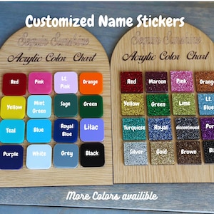 May include: Wooden display boards showcasing acrylic color swatches for custom name stickers. The boards feature a variety of colors, including red, pink, orange, yellow, green, blue, and purple, with glitter and solid finishes. Text reads "Customized Name Stickers" and "Acrylic Color Chart."