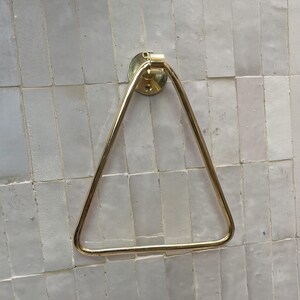 Close-up of polished brass towel ring on light tile wall