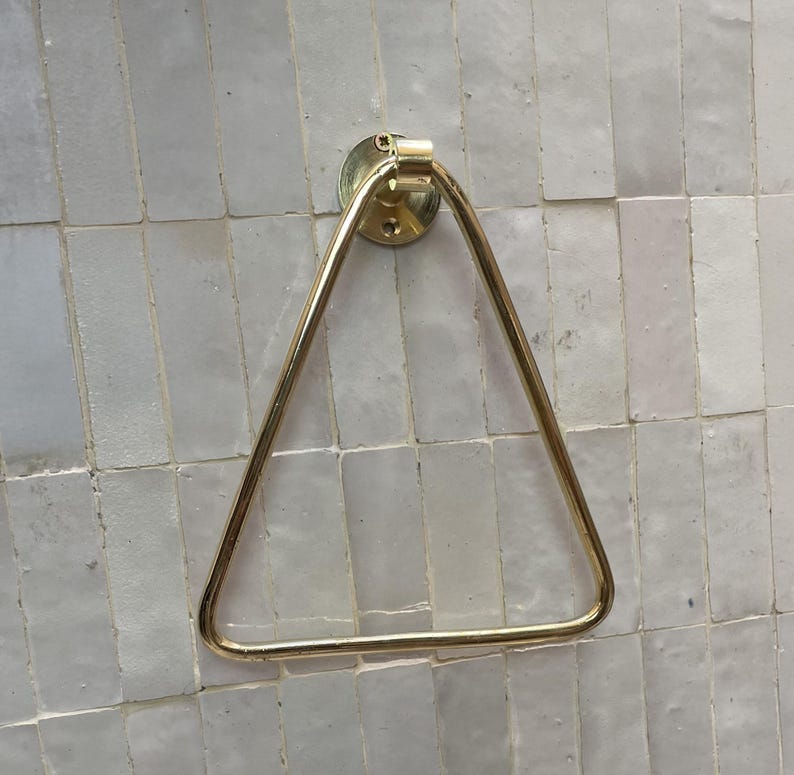 Close-up of polished brass towel ring on light tile wall