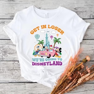 May include: White t-shirt with a graphic of Mickey Mouse and friends driving a pink car with the text "Get in Loser We're Going to Disneyland" in a retro font.