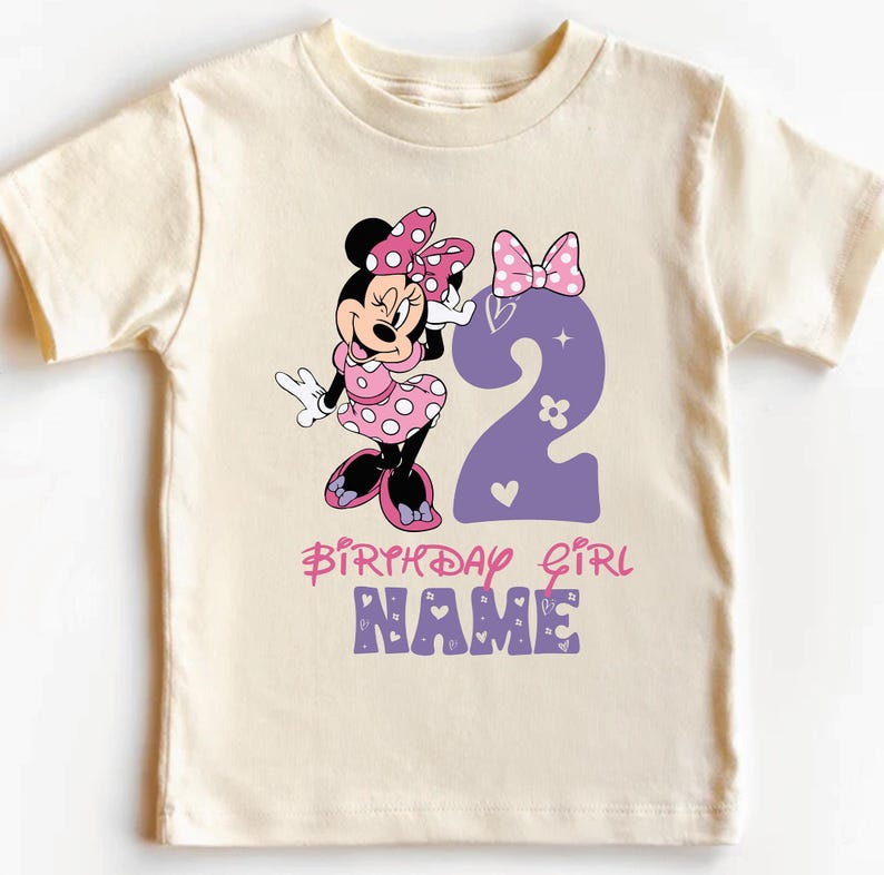 Może przedstawiać: Jasnobeżowa koszulka z postacią Minnie Mouse w r&oacute;żowe i białe kropki trzymającą fioletową dw&oacute;jkę. Na koszulce widnieje napis "Birthday Girl" i "NAME" w kolorze r&oacute;żowym i fioletowym.