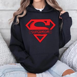 May include: Black hooded sweatshirt with a red Superman logo and the text "Supermom" printed on the front.