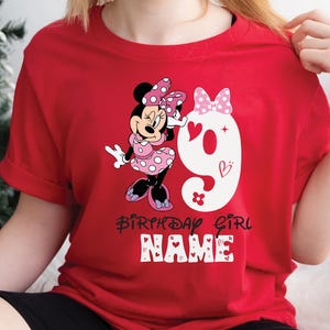 Może przedstawiać: Czerwona koszulka z białą cyfrą dziewięć i kresk&oacute;wkową postacią Minnie Mouse w r&oacute;żowej sukience w kropki. Na koszulce nadrukowany jest tekst "Birthday Girl" i "NAME".