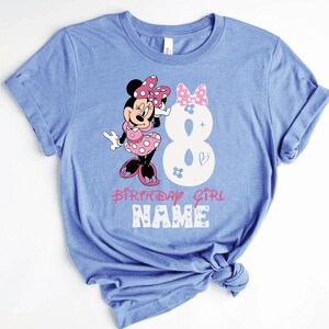Może przedstawiać: Niebieska koszulka z nadrukiem Minnie Mouse w kolorze r&oacute;żowym i białym. Nadruk zawiera cyfrę 8, słowa "Birthday Girl" i słowo "NAME".