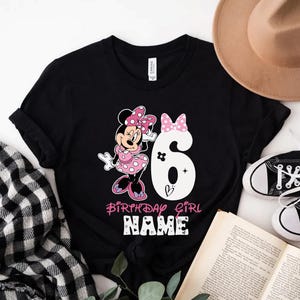 Może przedstawiać: Czarny T-shirt z grafiką Minnie Mouse w kolorze r&oacute;żowym i białym, białą cyfrą 6 i tekstem "Birthday Girl NAME".