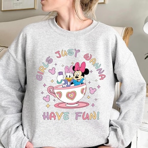 Pu&ograve; includere: Felpa grigia con una grafica di Minnie Mouse e Daisy Duck in una tazza da t&egrave;. Il testo "Girls Just Wanna Have Fun!" &egrave; stampato in colori arcobaleno.