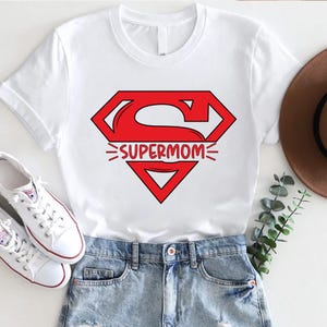 May include: White t-shirt with a red Superman logo and the text "SUPERMOM" printed on it.