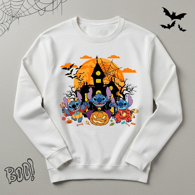 May include: White sweatshirt featuring a Halloween-themed graphic. The design includes three blue cartoon characters dressed in costumes, a jack-o'-lantern, a haunted house, bats, and the word "Boo!".