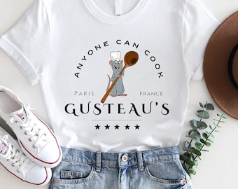May include: White t-shirt with a cartoon rat chef holding a wooden spoon. The text "Anyone Can Cook" is above the rat and "Paris Gusteau's France" is below the rat. Five stars are below the text.