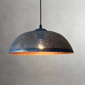 May include: A dome-shaped pendant light fixture with a dark blue, perforated metal shade. The shade has a warm, copper-colored interior and a single light bulb. The fixture hangs from a black cord.