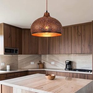 May include: A dome-shaped pendant light fixture with a metallic copper finish and a perforated pattern that allows light to shine through. The lamp hangs from a thin cord and features a warm, glowing interior surface visible from below.