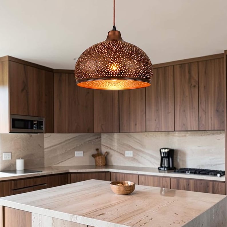 May include: A dome-shaped pendant light fixture with a metallic copper finish and a perforated pattern that allows light to shine through. The lamp hangs from a thin cord and features a warm, glowing interior surface visible from below.