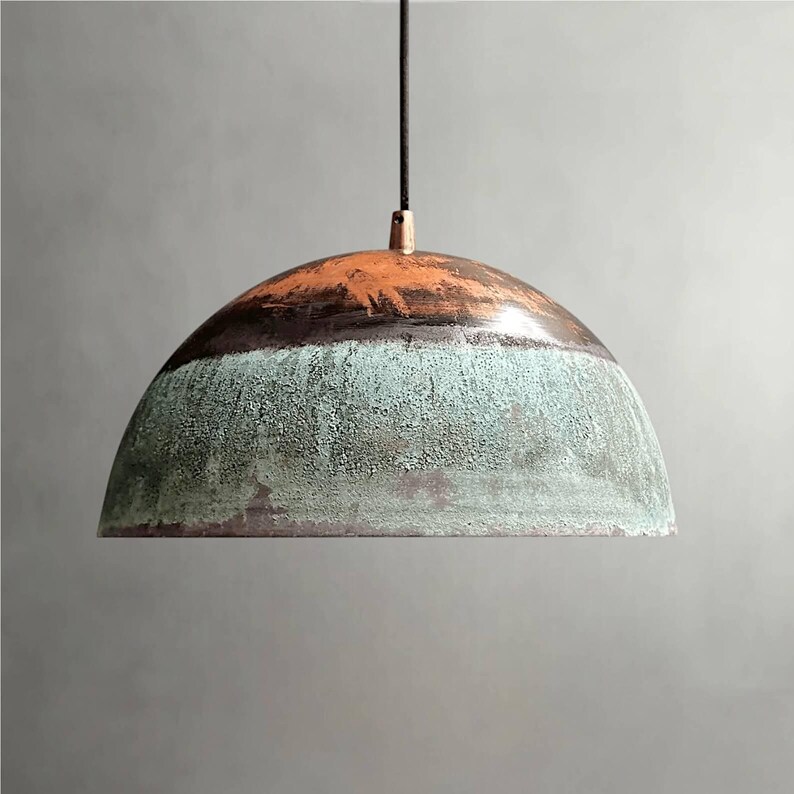 May include: A hanging pendant light with a dome-shaped shade. The shade features a color gradient, transitioning from a rusty orange at the top, through a dark brown band, to a textured turquoise-green at the bottom. The light hangs from a black cord.