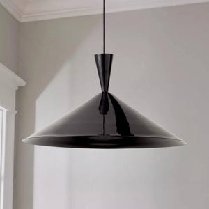 May include: A contemporary black pendant light with a conical shade and a glossy finish. The light fixture hangs from the ceiling via a thin black cord, offering a minimalist design. The shade's diameter is approximately 76 cm.