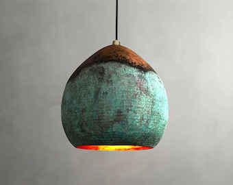 May include: A hanging pendant light with a unique, textured surface. The top is a warm brown, transitioning to a turquoise-green body. The light fixture has a black cord and a brass-colored accent at the top.