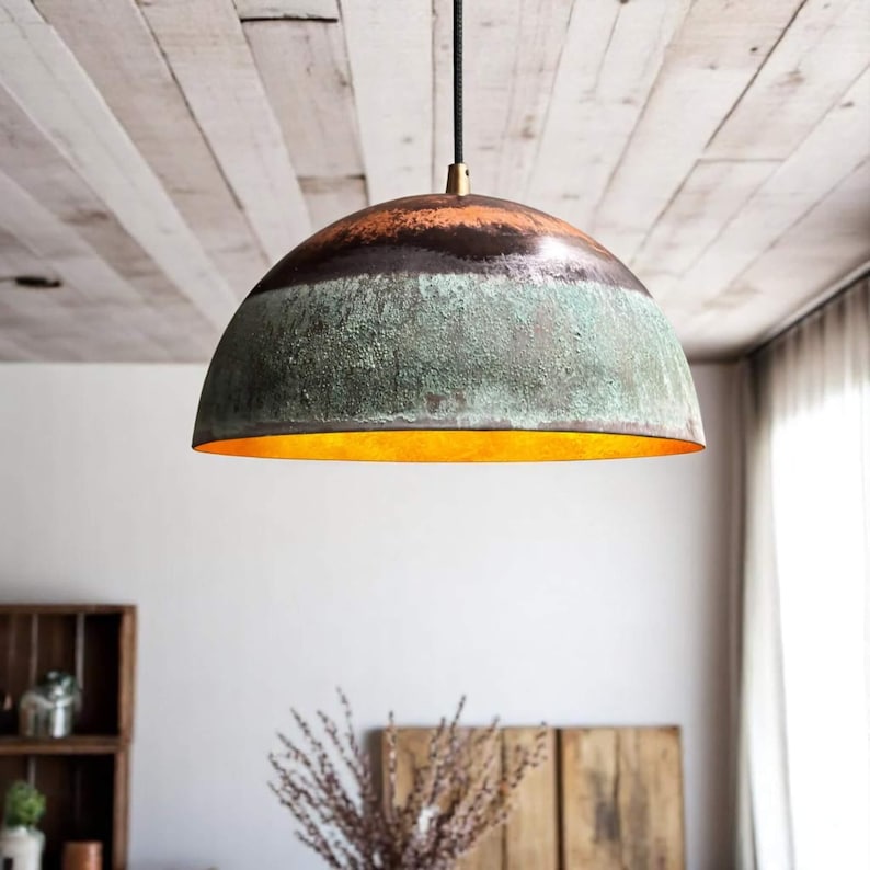 May include: A dome-shaped pendant light fixture with a textured, multi-toned finish. The top section is dark brown, transitioning to a green-blue midsection, and a bright orange interior. It hangs from a black cord with a brass fitting.