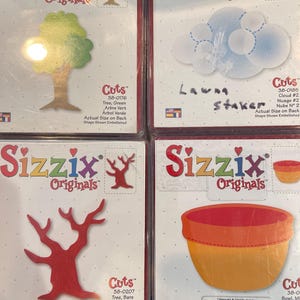 May include: Four Sizzix Originals die-cut sets. One shows a green tree, another a cloud, a third a bare tree, and the last a bowl. Each set includes the "Cuts" logo and product information.
