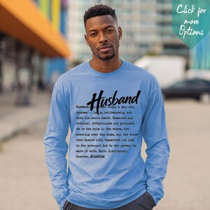 Puede incluir: Una camiseta de manga larga de color azul claro con texto en negro que define la palabra Husband. El texto dice: Husband noun: A man who chooses - daily, deliberately, and with his whole heart. Romantic and rational. Affectionate and grounded. #IAMHIM