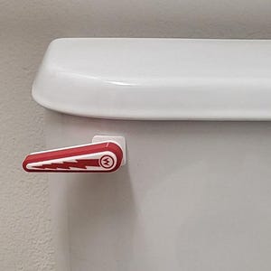 May include: A red and white toilet flush lever with a lightning bolt design and a circular logo. The lever is attached to a white toilet tank. The design is a bold, graphic style.