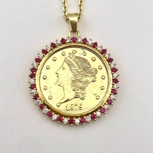 May include: A gold coin pendant necklace. The coin features a profile of a woman and the year 1879. The coin is surrounded by a halo of alternating red and white gemstones, and hangs from a gold chain.