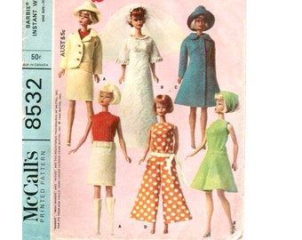 May include: A vintage McCall's 8532 pattern for Barbie doll clothes. The pattern includes five different outfits: a white dress with lace, a red sweater with a white skirt, a blue coat with a white hat, a green dress, and a polka dot jumpsuit with a white belt. The pattern is titled "Barbie Doll's Instant Wardrobe" and is priced at 50 cents.