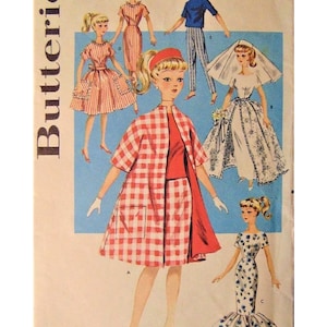 Könnte beinhalten: Ein Vintage-Schnittmuster zum Nähen von Puppenkleidern. Das Schnittmuster ist für eine Puppe, die 29,2 cm lang ist. Das Schnittmuster enthält Anleitungen zum Nähen eines rot-weiß karierten Kleides, eines blau-weiß gemusterten Kleides, eines weißen Brautkleides, eines roten Kleides und eines blau-weiß gestreiften Hosenanzugs. Die Schnittmuster-Nummer ist 9993 und der Preis beträgt 50 Cent.