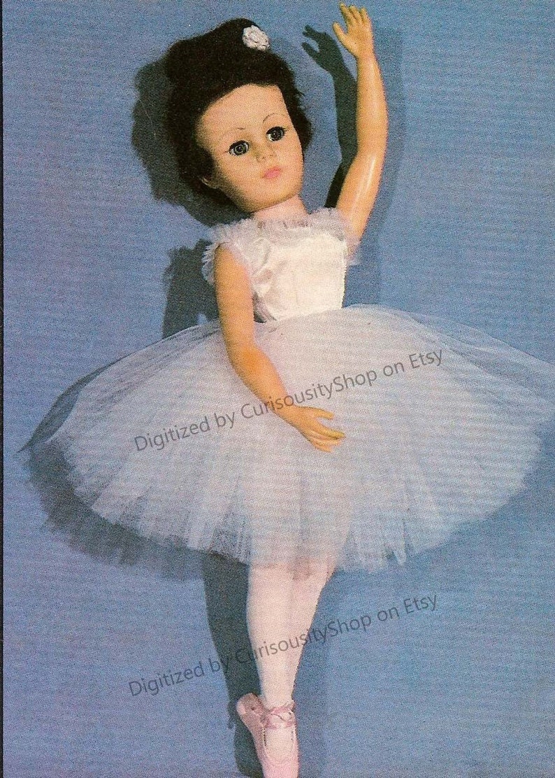 May include: A vintage ballerina doll wearing a white satin bodice and a light blue tulle tutu. The doll has dark hair and blue eyes and is posed with one arm raised.
