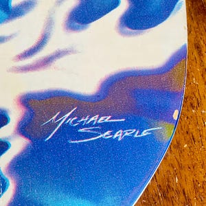 May include: A blue and white abstract painting with a signature that reads "Michael Searle".