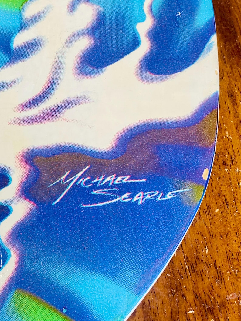 May include: A blue and white abstract painting with a signature that reads "Michael Searle".