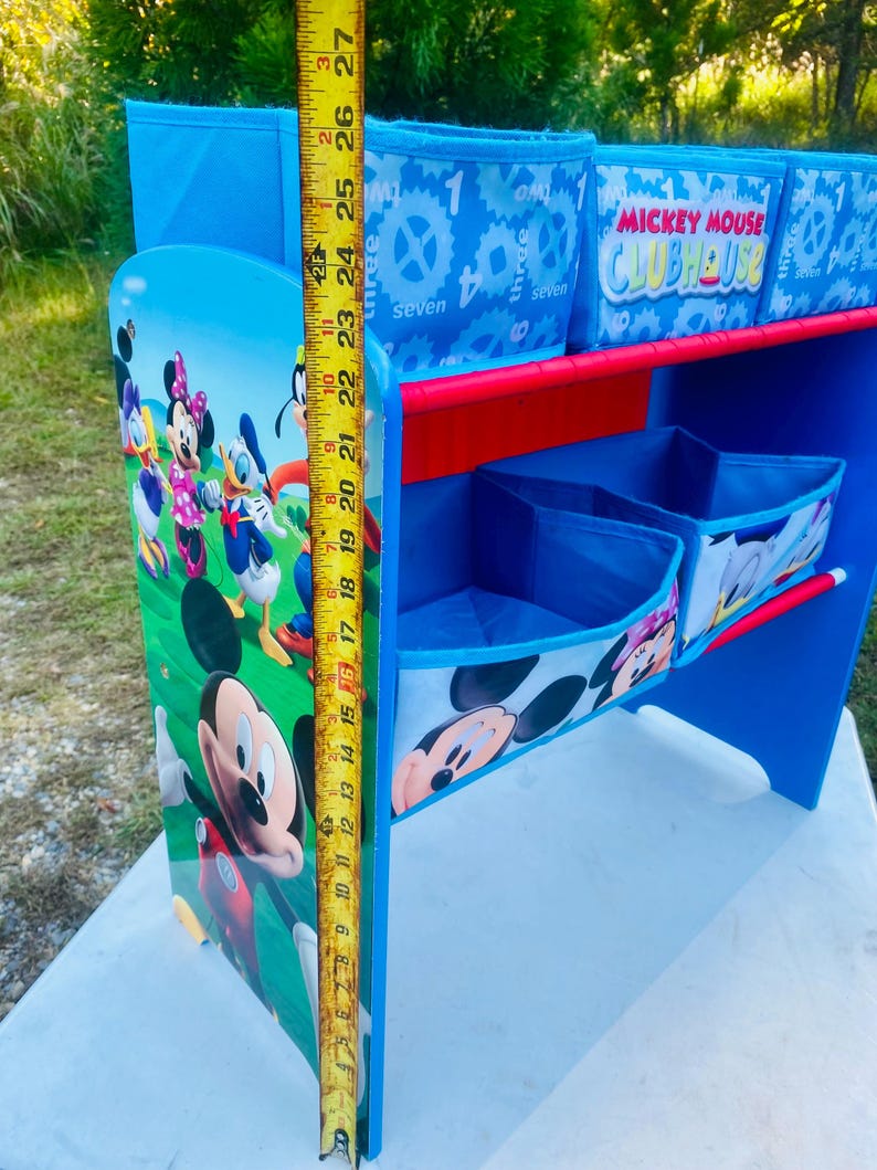 Puede incluir: Un escritorio azul y rojo de Mickey Mouse Clubhouse con compartimentos de almacenamiento. El escritorio presenta im&aacute;genes de Mickey Mouse, Minnie Mouse, Donald Duck y otros personajes. El escritorio mide aproximadamente 69 cm de alto.