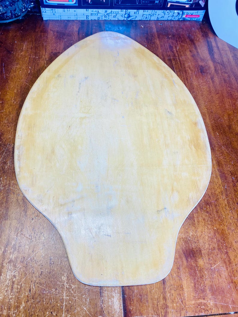 May include: A light brown wooden pizza peel with a rounded, teardrop shape.