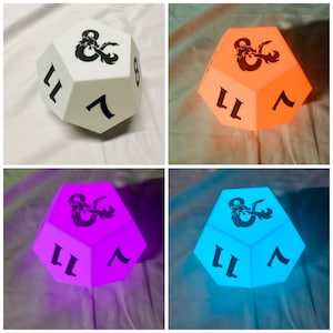 Könnte beinhalten: Ein vielseitiger Dungeons & Dragons Würfel in vier verschiedenen Farben: Weiß, Orange, Lila und Blau. Jeder Würfel zeigt das D&D-Logo und schwarze Zahlen. Ein einzigartiger Dekorationsartikel für Tabletop-Gaming-Enthusiasten.