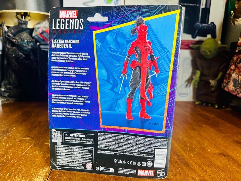 K&ouml;nnte beinhalten: Marvel Legends Series Actionfigur von Elektra Natchios Daredevil, in einem rot-schwarzen Kost&uuml;m mit Sai-Waffen. Die Figur ist in einer blau-violetten Box mit Charakterdetails und dem Marvel-Logo verpackt.