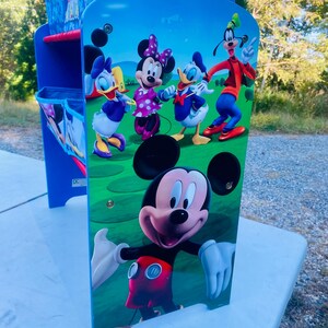 Puede incluir: Un escritorio azul y blanco para ni&ntilde;os con Mickey Mouse y sus amigos. El escritorio presenta una colorida ilustraci&oacute;n de Mickey, Minnie, Donald, Daisy y Goofy en el panel frontal. El escritorio tiene un marco azul y un compartimento de almacenamiento.
