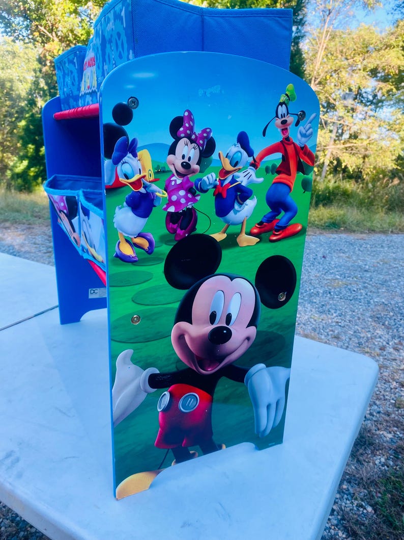 Puede incluir: Un escritorio azul y blanco para ni&ntilde;os con Mickey Mouse y sus amigos. El escritorio presenta una colorida ilustraci&oacute;n de Mickey, Minnie, Donald, Daisy y Goofy en el panel frontal. El escritorio tiene un marco azul y un compartimento de almacenamiento.