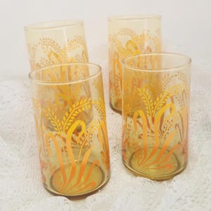 May include: A white ceramic mug with a black handle and the text "But First, Coffee" in a bold, black font. The mug is set against a blurred background, suggesting a cozy setting.