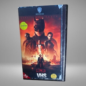 May include: A sealed VHS tape of the movie "The Batman" featuring a promotional image of the main characters. The cover has a red and black color scheme with the text "Unmask the Truth" and "Adventure". The VHS tape is in a plastic sleeve.
