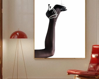 May include: A framed print featuring a black-clad leg and foot wearing a high-heeled shoe adorned with rhinestones. The foot balances a martini glass with an olive. The image is set against a white background.
