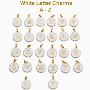 Puede incluir: Una colecci&oacute;n de dijes redondos blancos con letras doradas del alfabeto de la A a la Z. Cada colgante circular tiene una superficie blanca lisa con un borde dorado y una peque&ntilde;a argolla en la parte superior para joyer&iacute;a.